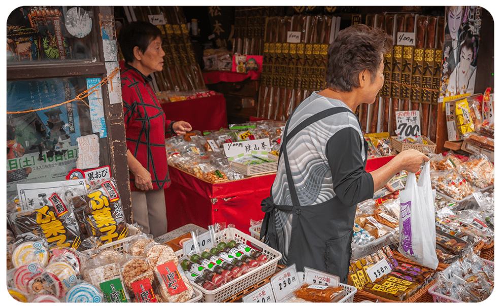 Assortment of Japanese dagashi snacks, being sold by senior women including sweet and savory treats popular in TokyoTreat.